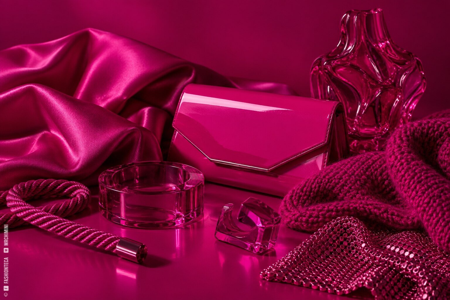 Bodegón magenta con satén, punto, laca, vidrio, cordón y malla metálica sobre fondo magenta