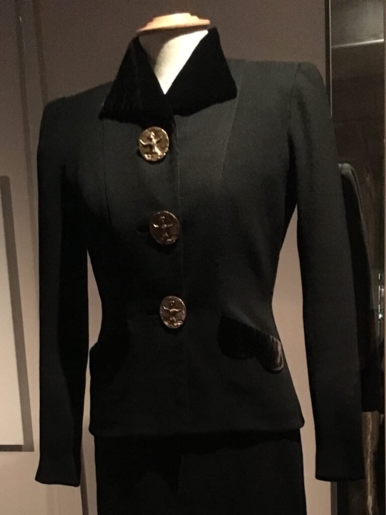 Tailleur de Elsa Schiaparelli de 1938–1939 con chaqueta estructurada y detalles decorativos.