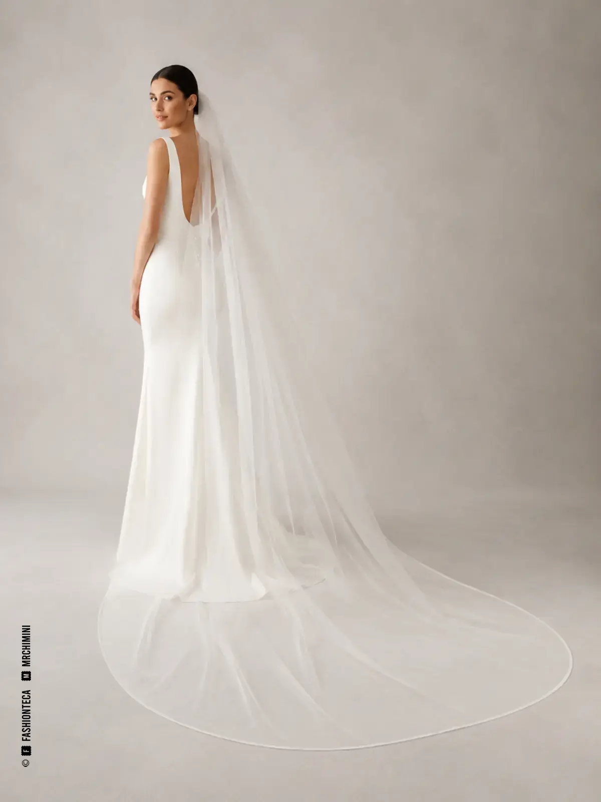 Novia con velo capilla blanco que se prolonga moderadamente por el suelo detrás del vestido.