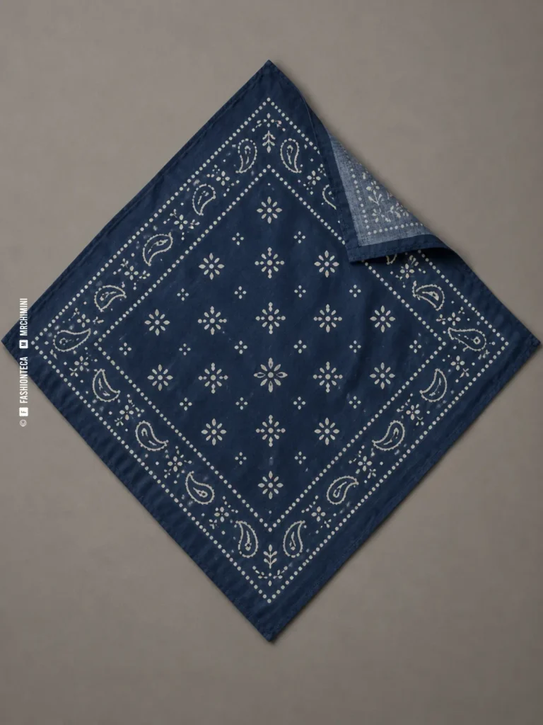 bandana cuadrada azul índigo de algodón con borde y motivos blancos, extendida en rombo sobre fondo gris cálido
