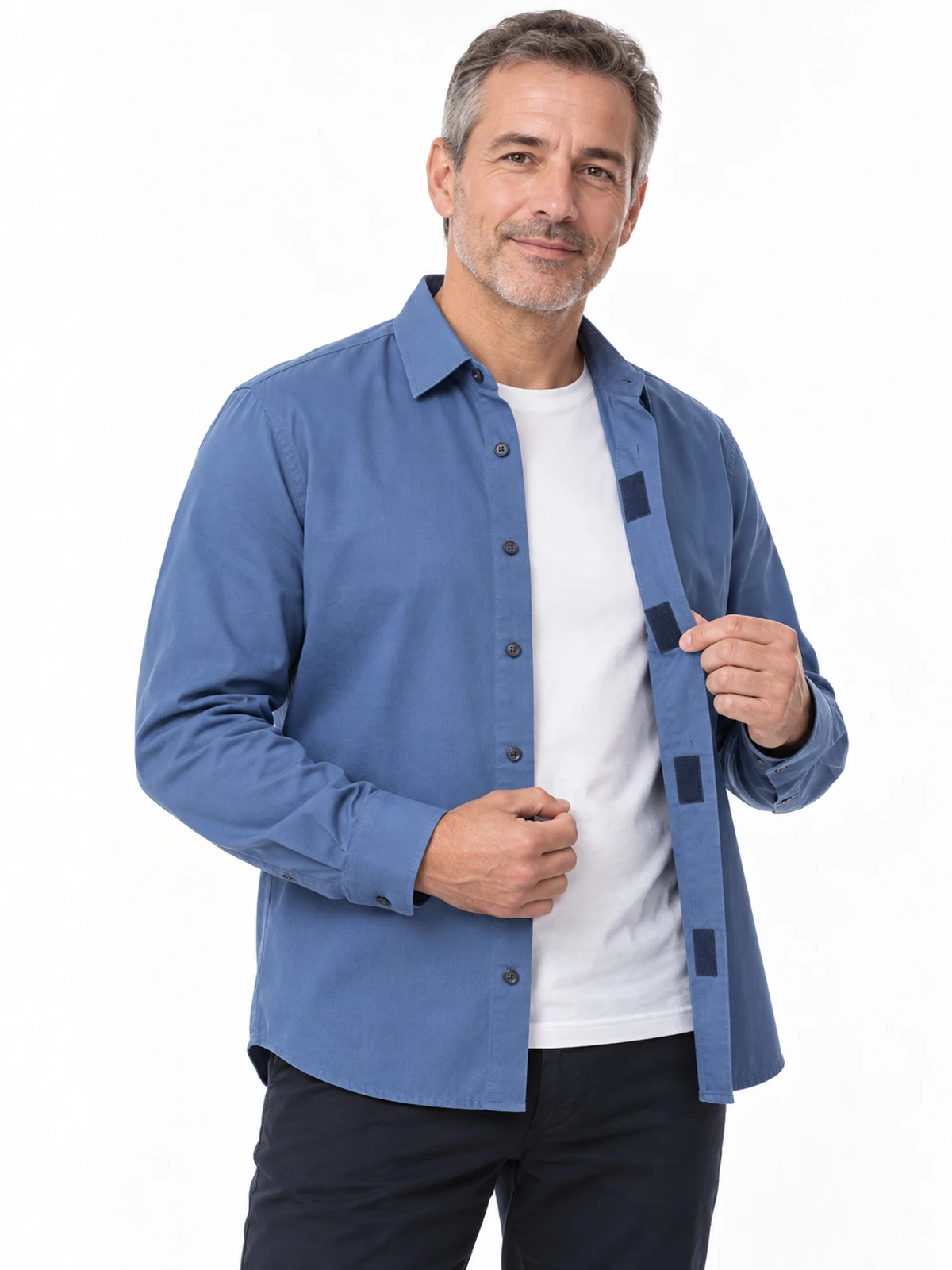 Persona adulta mostrando la apertura frontal de una camisa azul con cierres ocultos de gancho y bucle sobre una camiseta blanca.
