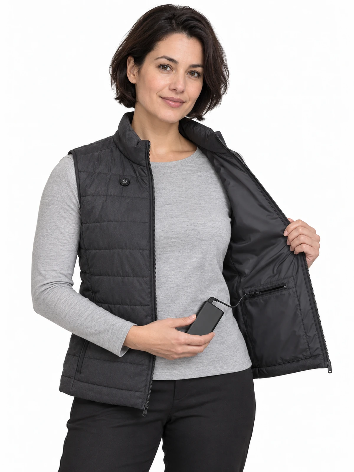 Persona adulta con chaleco acolchado calefactable abierto, mostrando el bolsillo interior y una pequeña batería extraíble sin marcas.