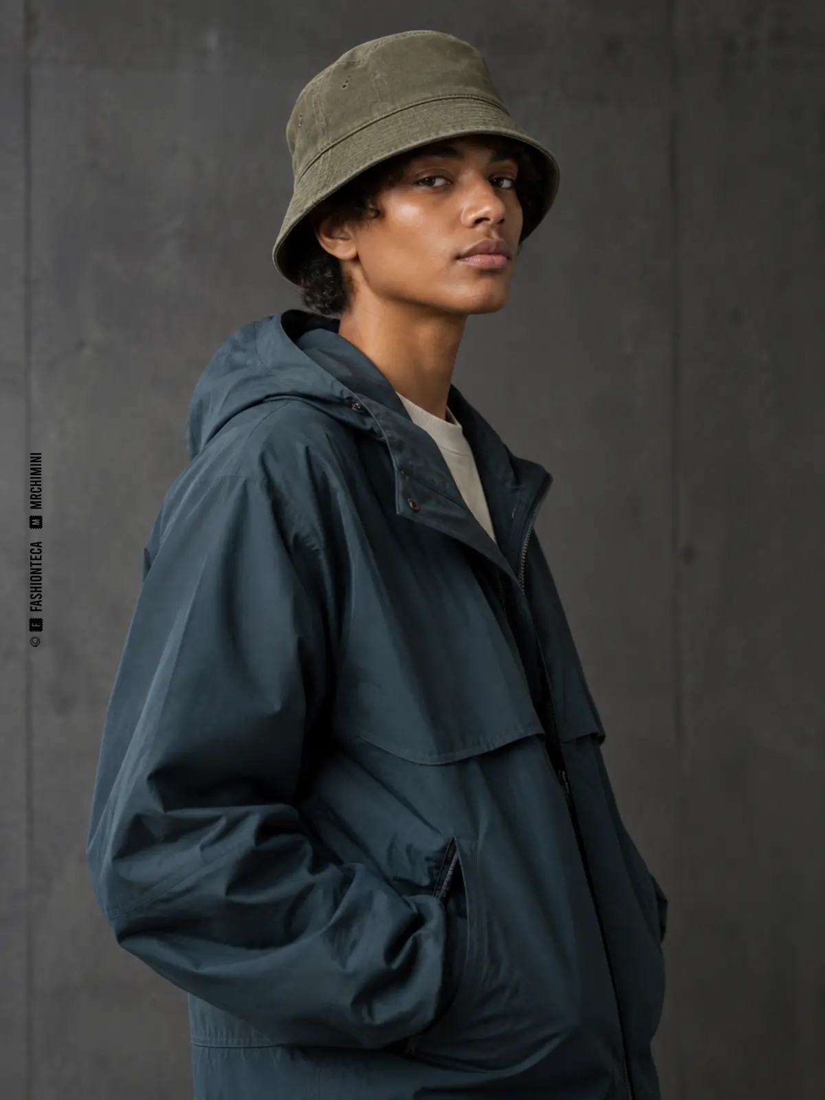 modelo con chaqueta técnica azul grisácea y sombrero bucket de sarga verde oliva con ala pespunteada hacia abajo